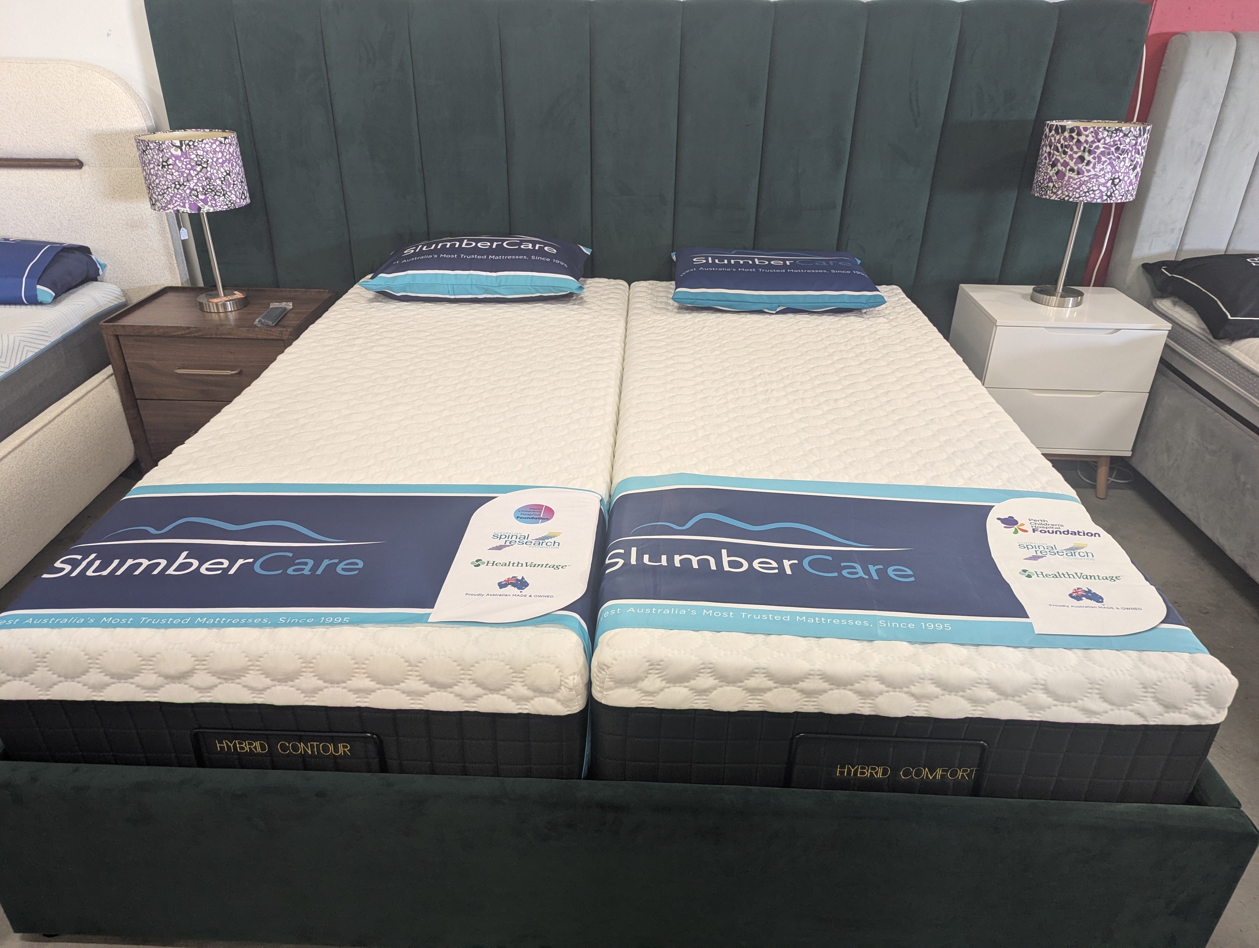 Hybrid contour mattress set on bed frame, white tops with blue trims and dark sides.