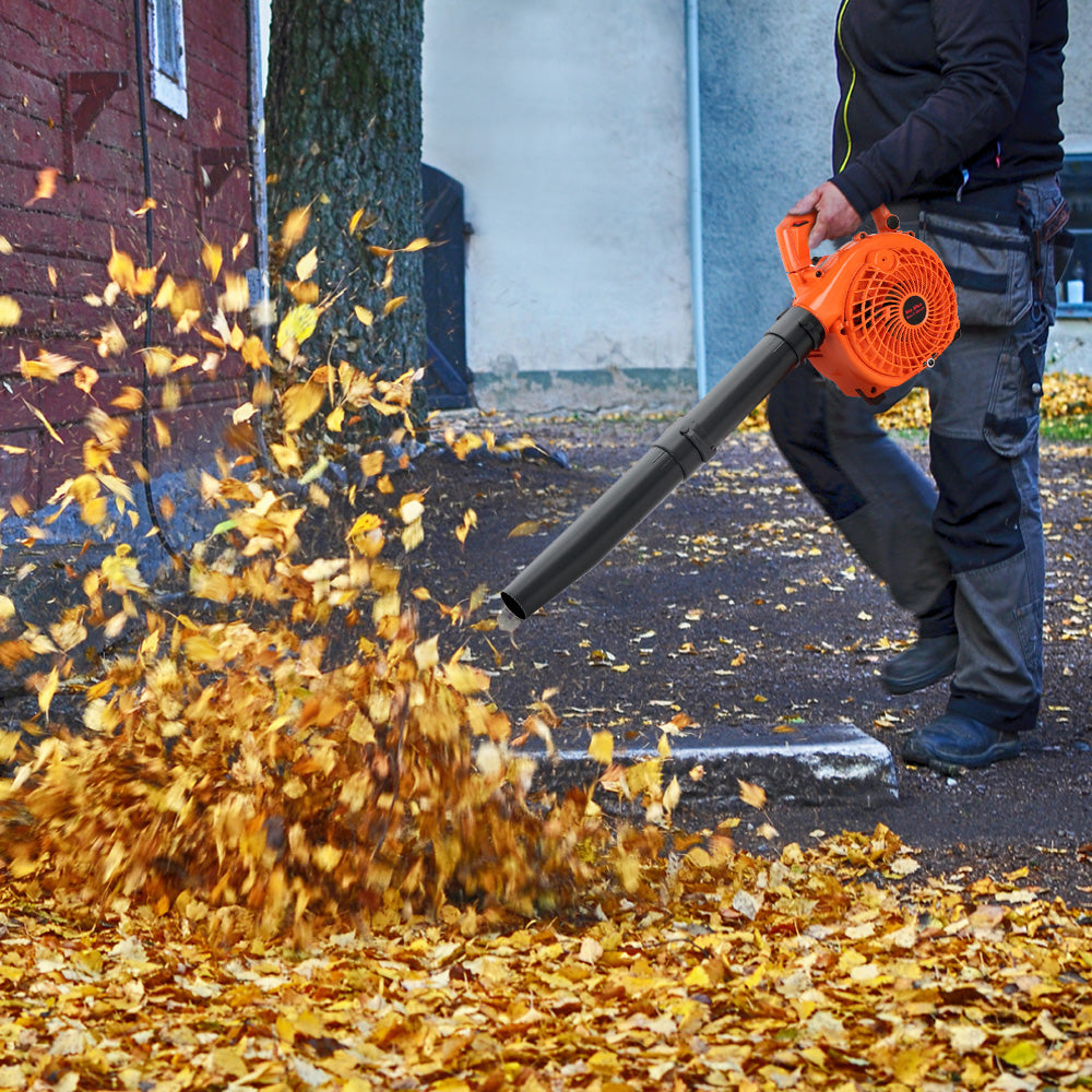 Person using orange leaf blower vacuum to clear leaves from a paved area