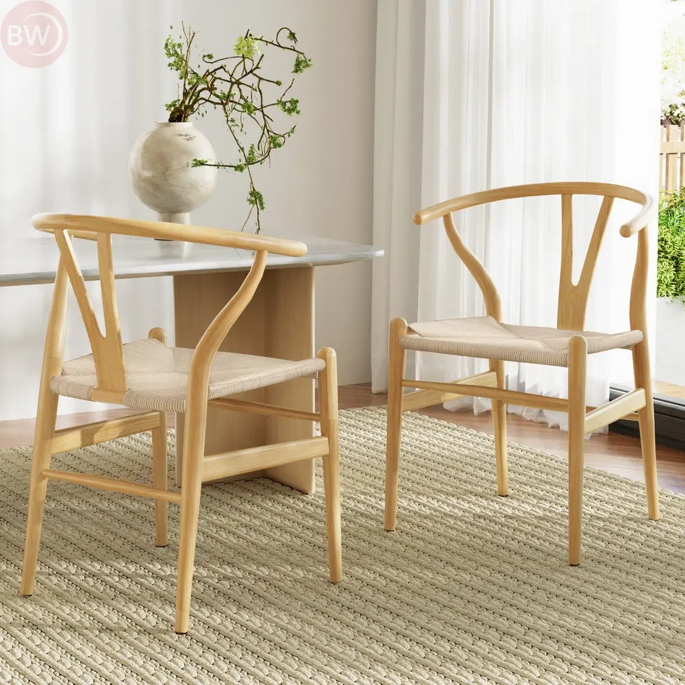 Two wooden dining chairs with wishbone backs and beige woven seat cushions