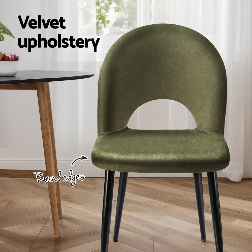 Velvet dining chair, olive green round-edged seat, curved back cutout, black metal legs.