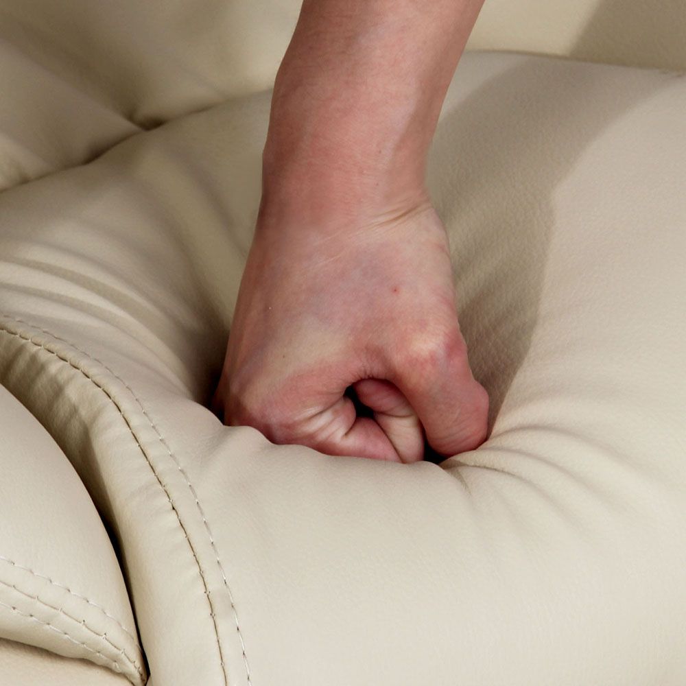 Beige leather-look upholstery close-up with stitched seams and padded arm area