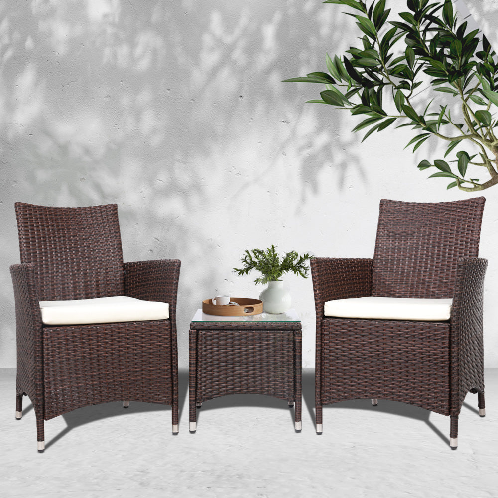 Outdoor bistro set with two brown wicker chairs, white seat cushions, and small table