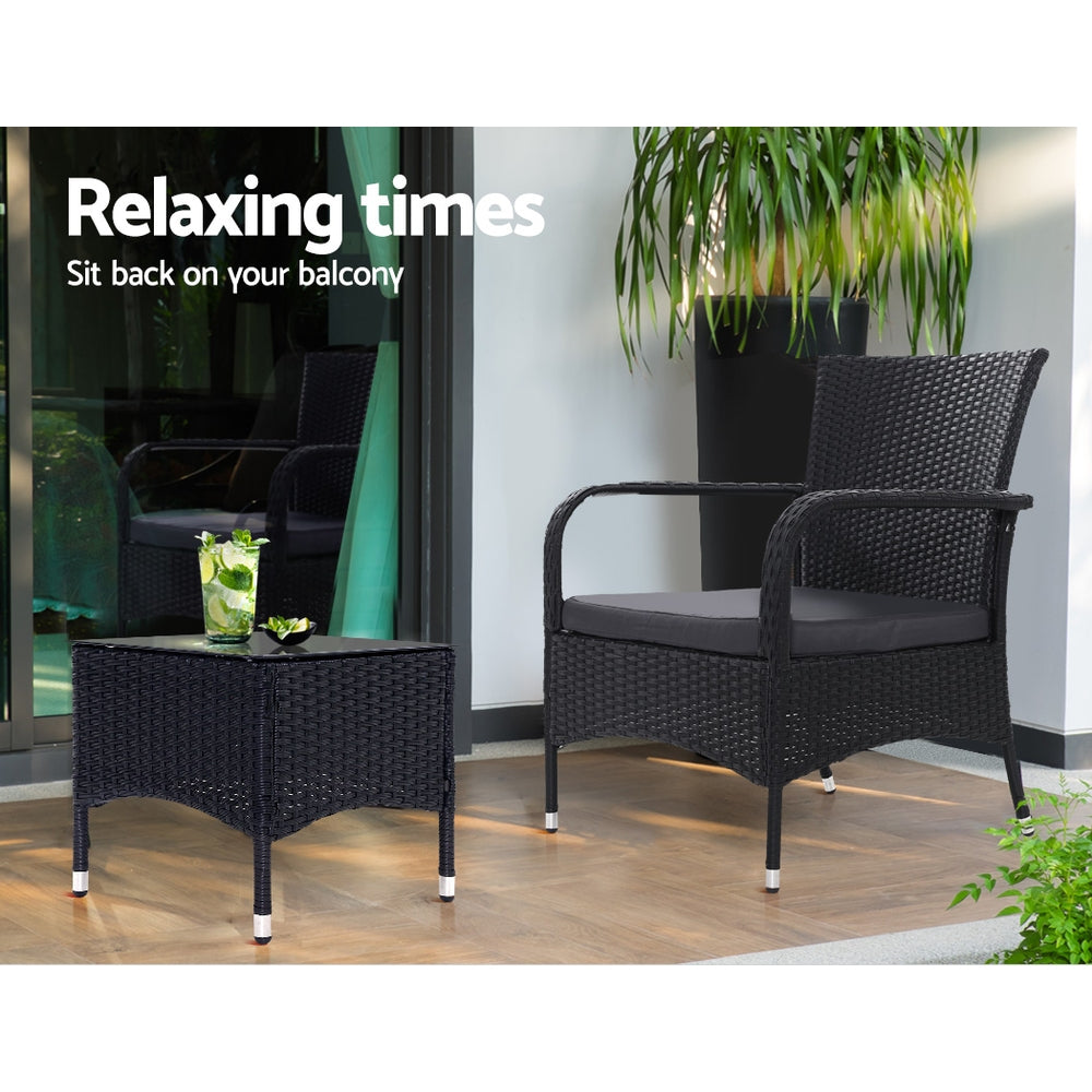 Outdoor bistro set with two black wicker armchairs and a matching side table on patio