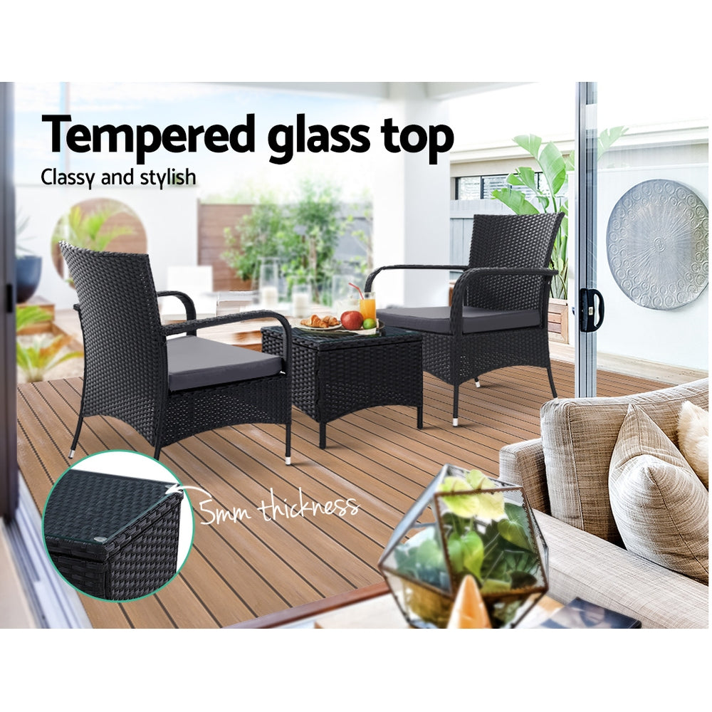 Outdoor bistro set with two black wicker armchairs and a square table with glass top