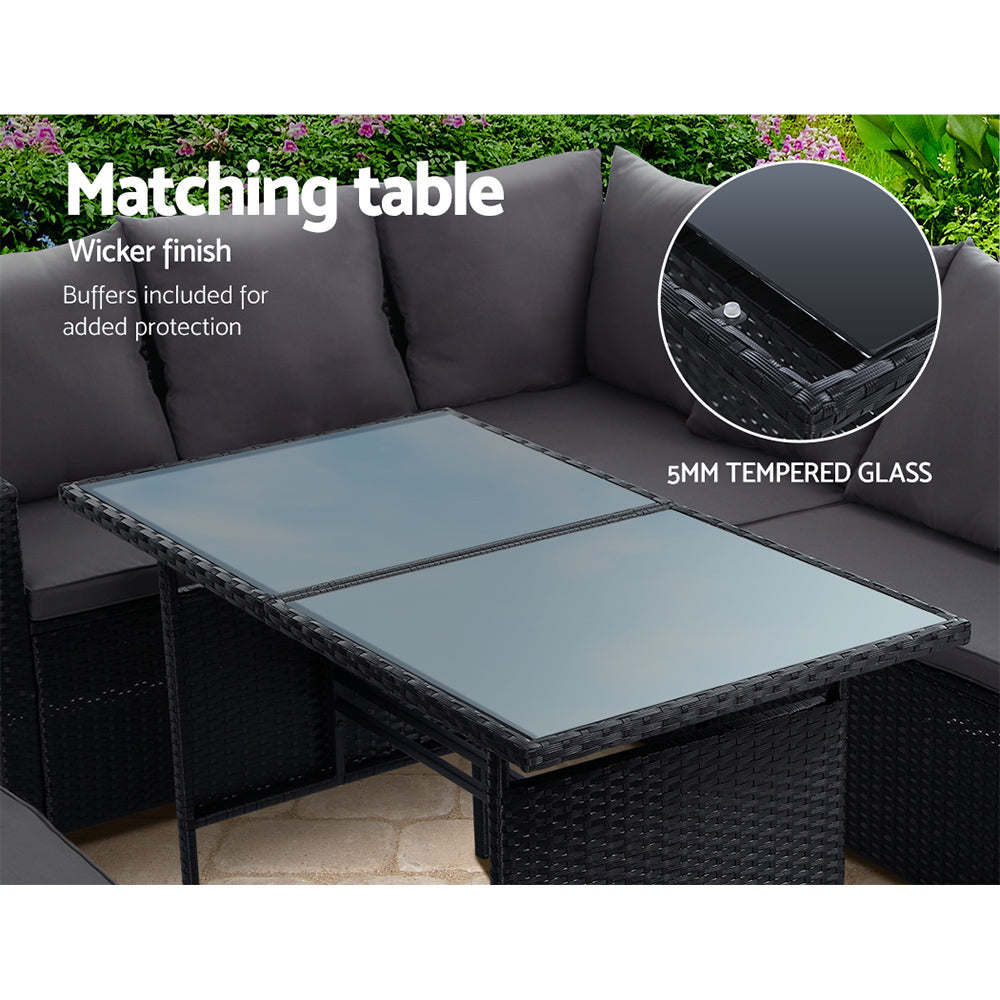 Tempered glass-top dining table with black wicker frame and gray seat cushions