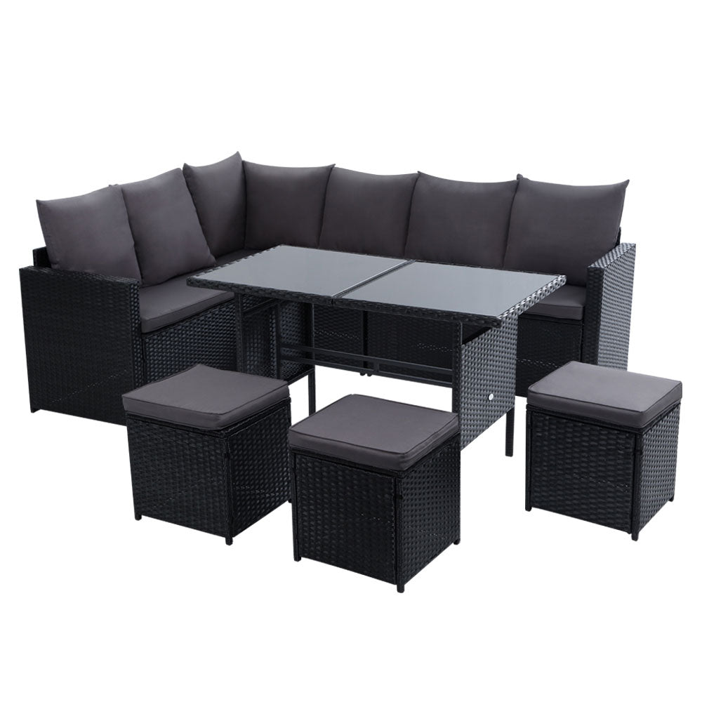 Black wicker outdoor dining lounge set with gray cushions, glass table, and ottomans
