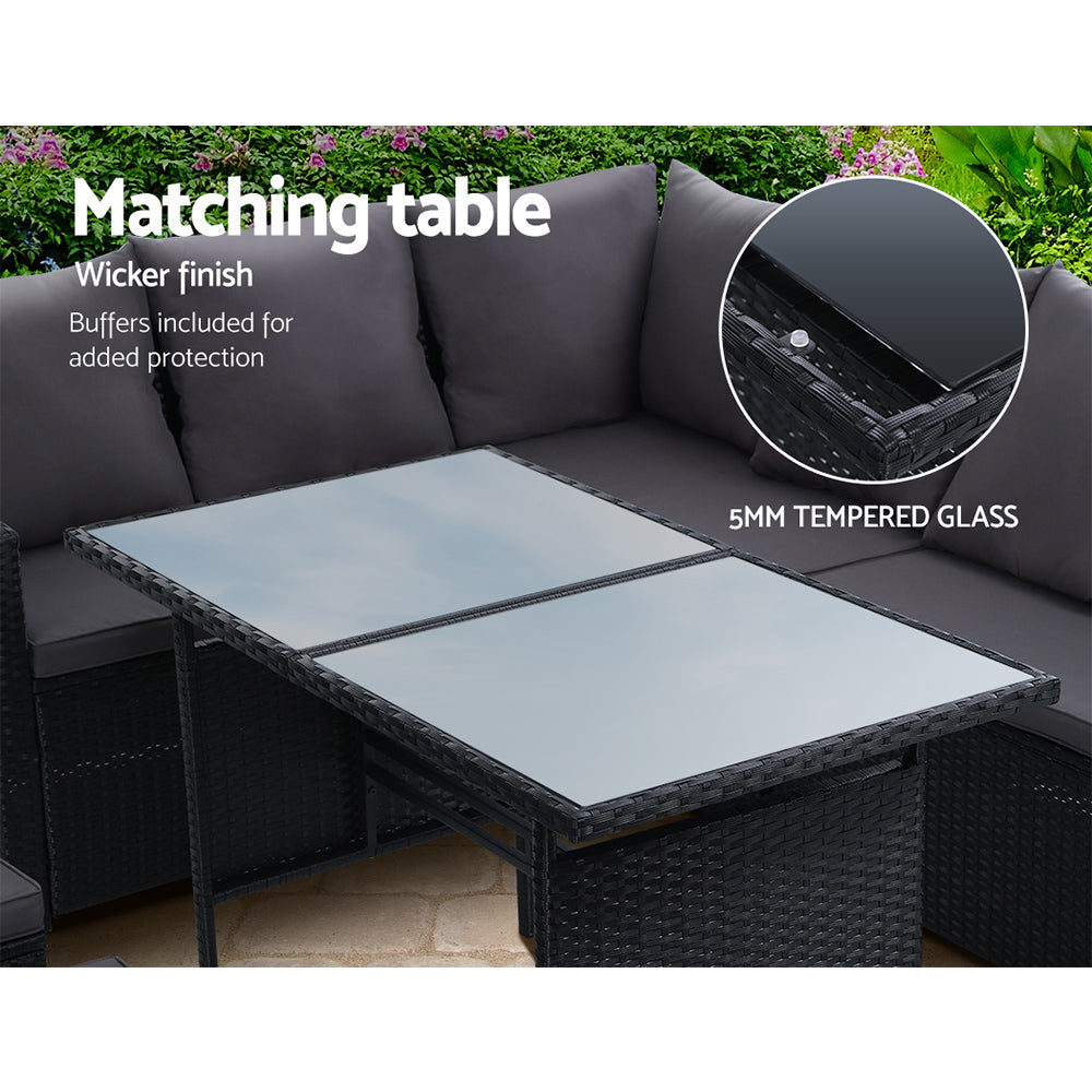 Outdoor dining table with tempered glass top and black wicker base, matching gray sofa cushions