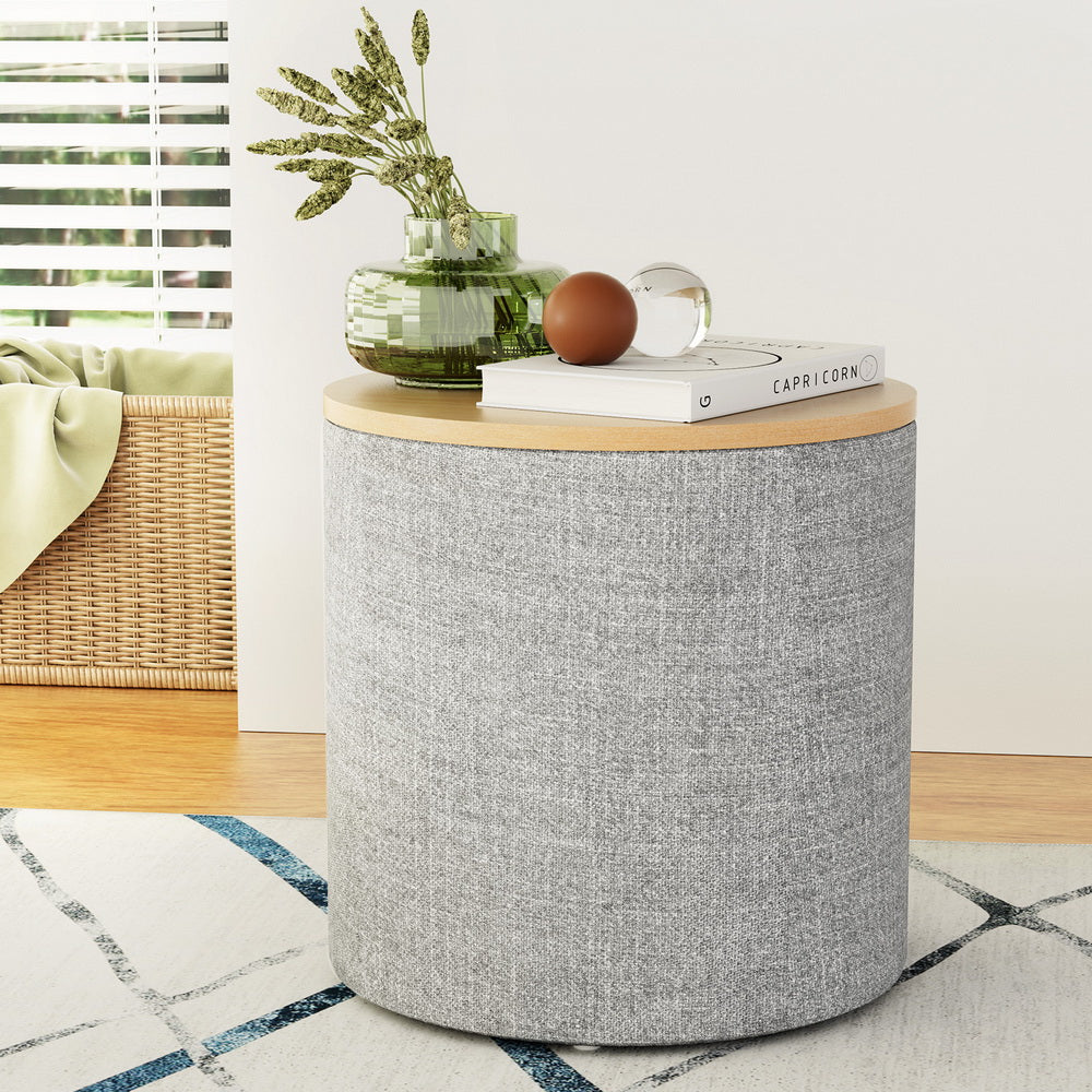 Grey round storage ottoman with light wood-tone top and upholstered fabric body.