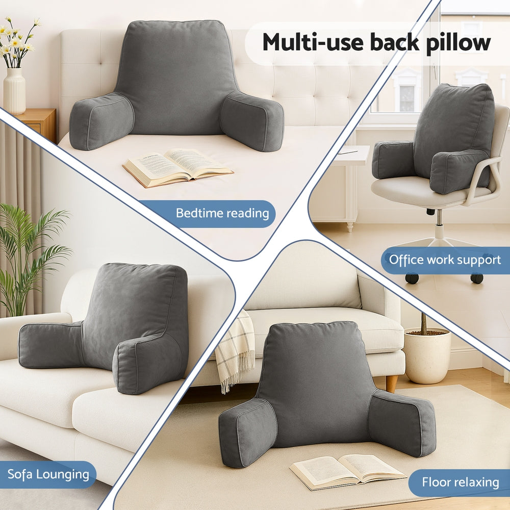 Grey multi-use backrest pillow with padded arms, placed on a sofa for reading