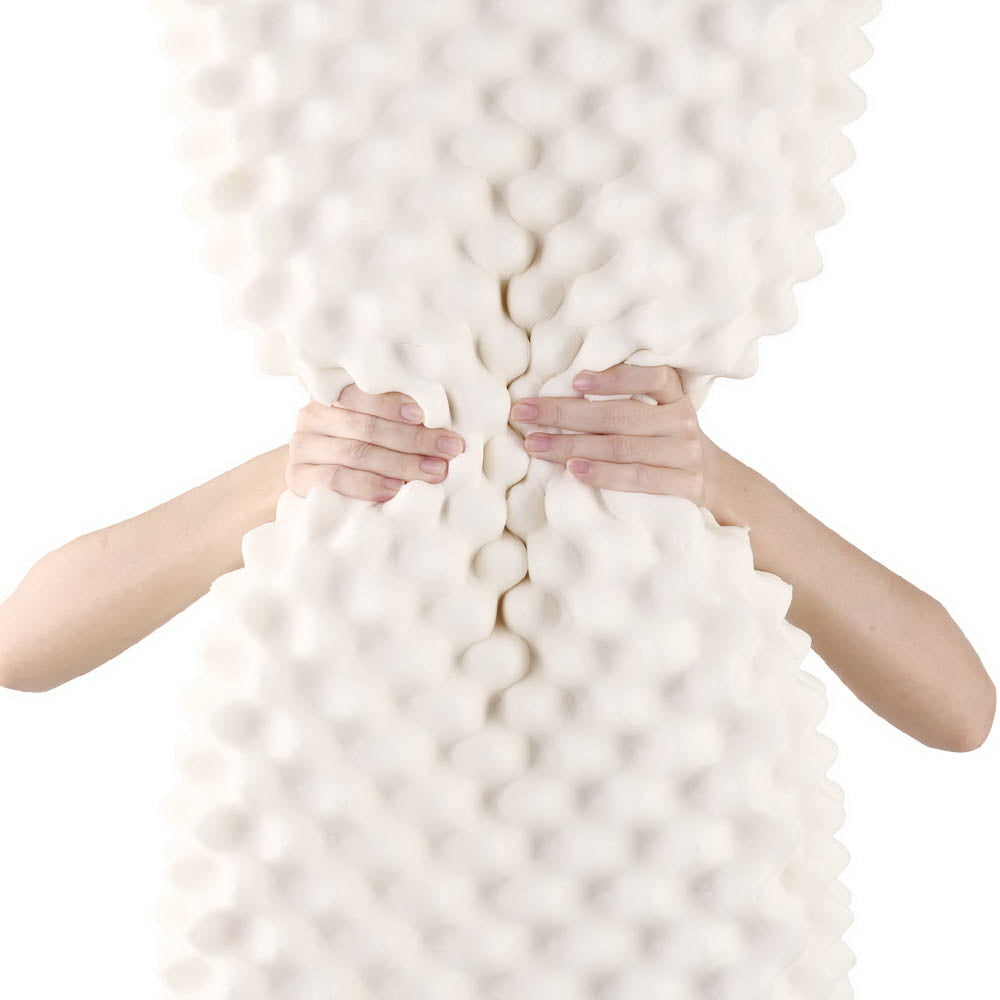 Hands pressing creamy white bumpy latex surface for natural latex pillow comfort