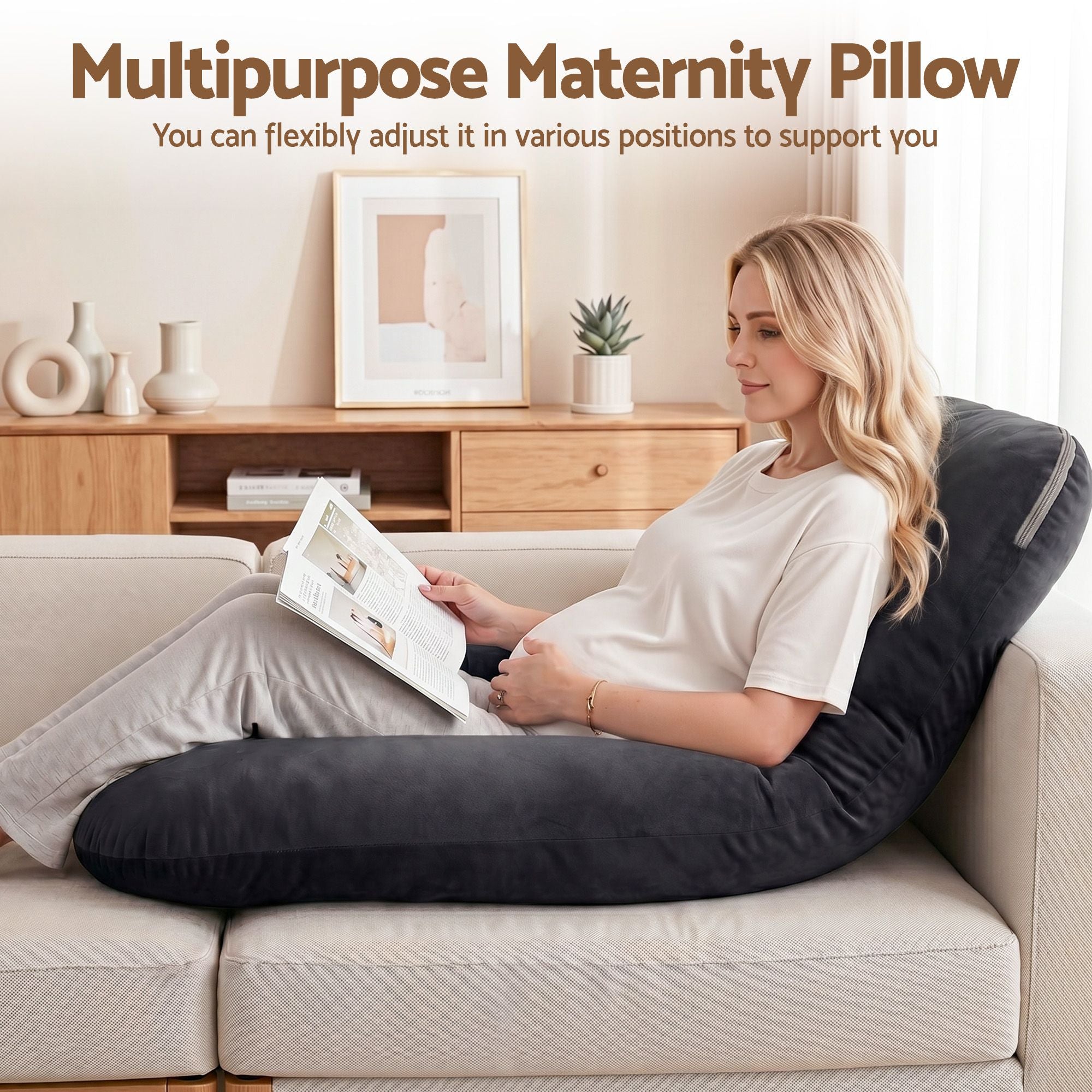 Dark grey pregnancy body pillow next to a seated woman on a sofa bed