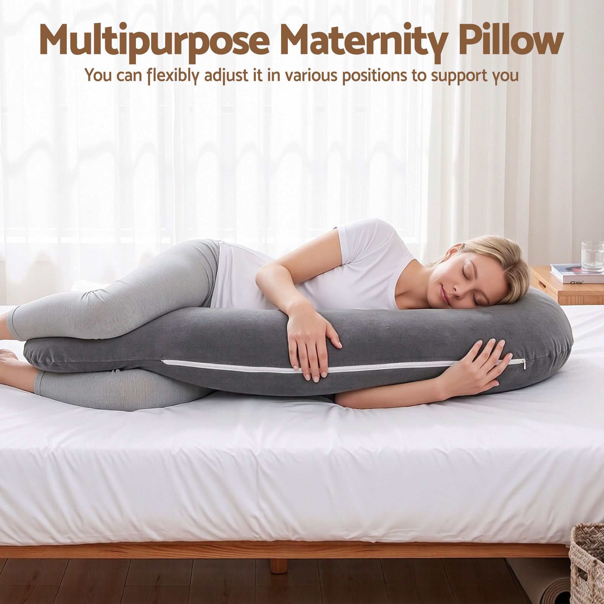 Grey multipurpose maternity body pillow laid across a bed, curved support shape.
