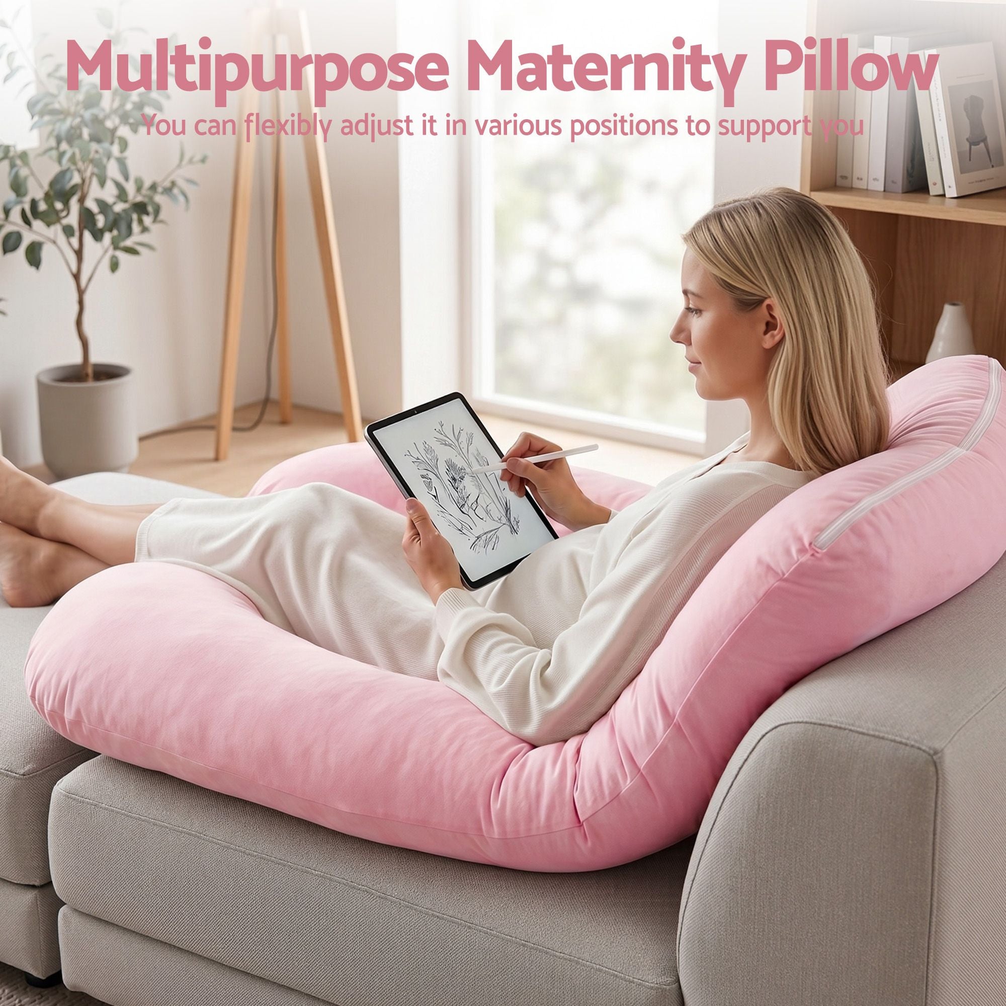 Pink U-shaped full body maternity pillow with person reading while reclined