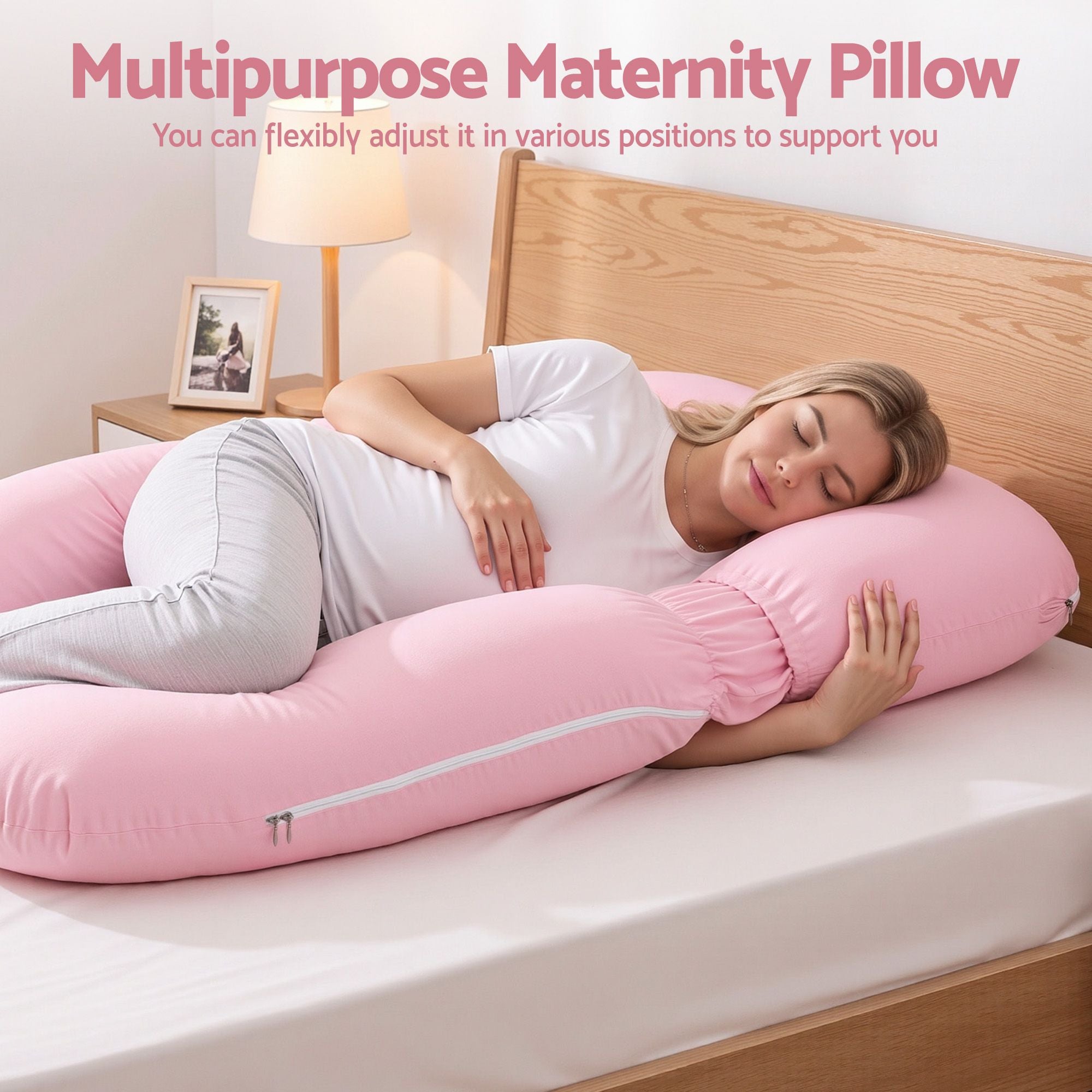 Pink U-shaped maternity pillow supporting a person lying on a bed