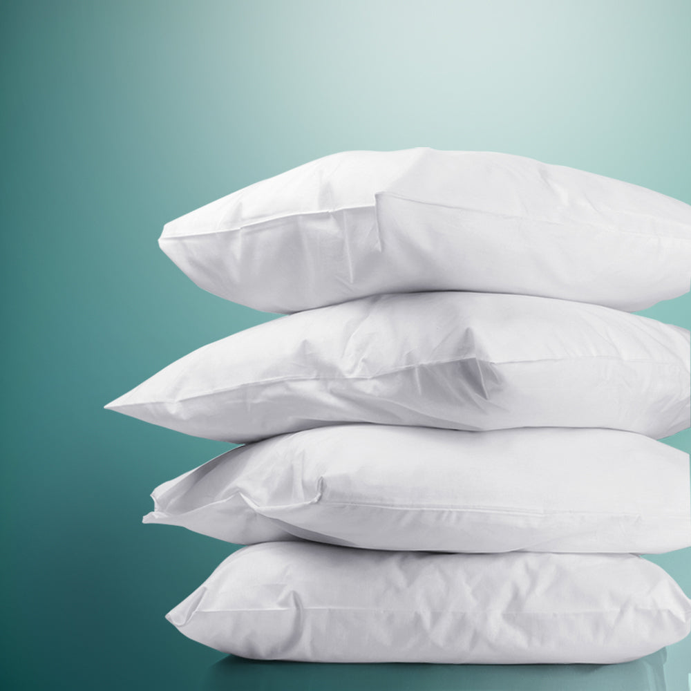 Set of four white bed pillows, stacked and plump with smooth seams