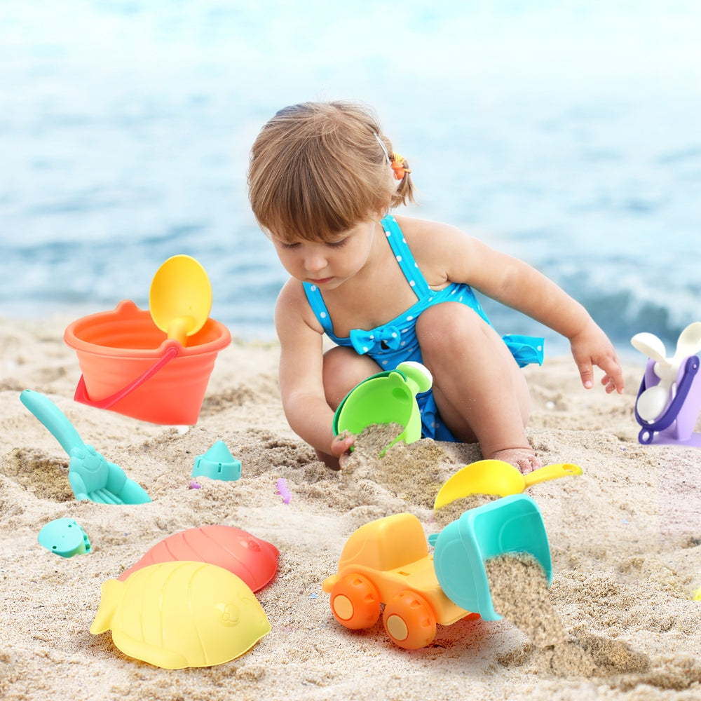 Kids sand play tool kit with buckets, shovels, windmill and shell molds near beach sand