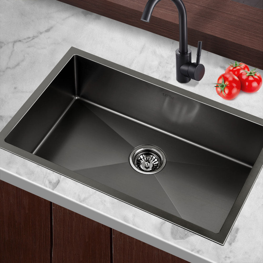 Black single-bowl kitchen sink with round drain strainer and deck-mounted faucet