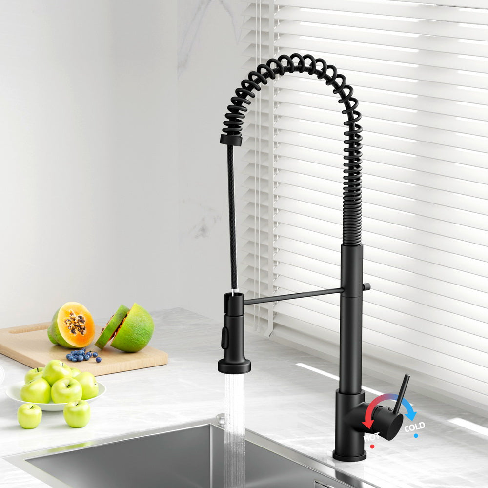 Black pull-down kitchen mixer tap above sink with coiled hose and control lever