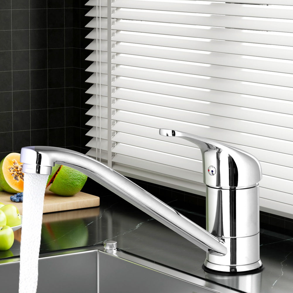 Chrome kitchen sink mixer tap with long curved spout and lever handle in use