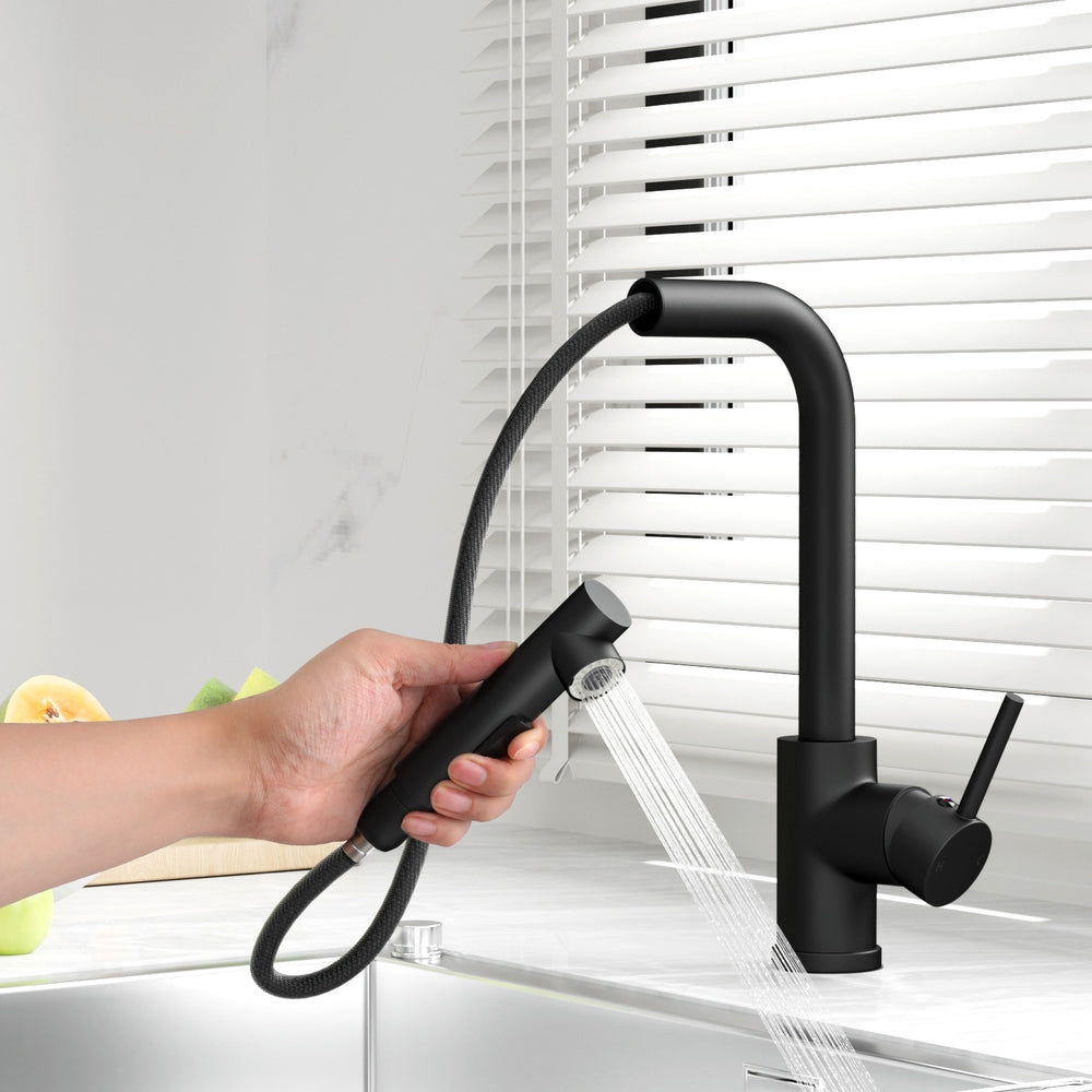 Black pull-out kitchen faucet with handheld sprayer releasing a steady stream of water