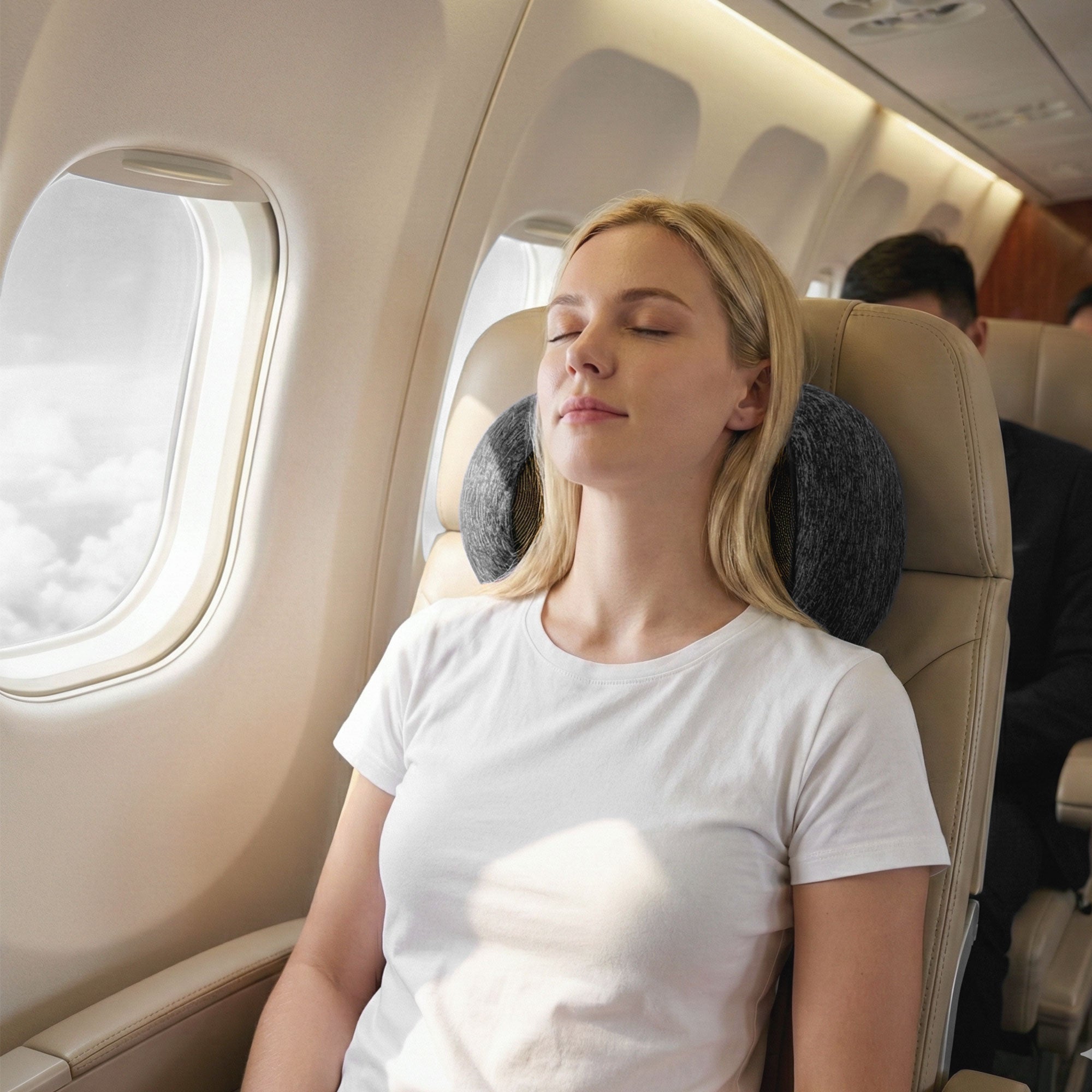 Dark grey travel neck pillow used on an airplane seat for neck support