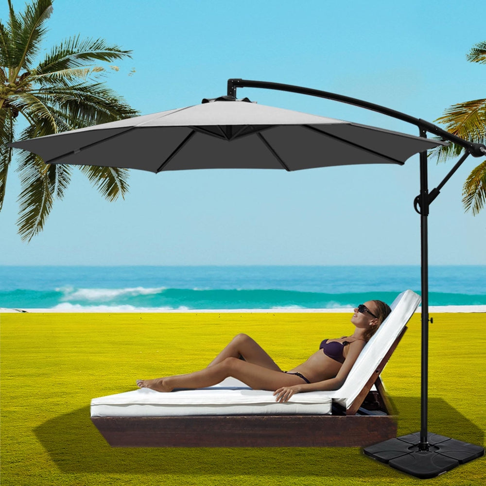 Grey open cantilever patio umbrella with curved arm and square weighted base