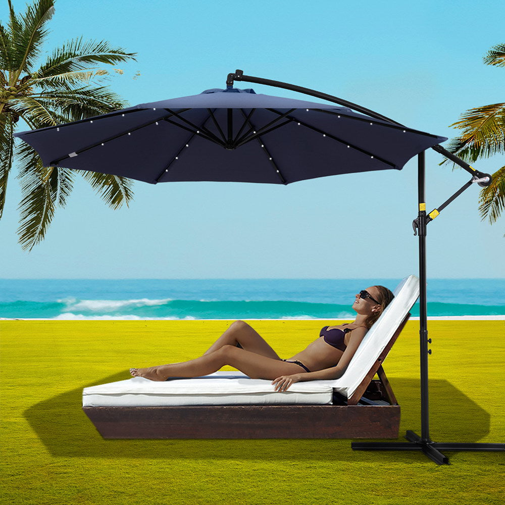 Open cantilever beach umbrella with navy canopy and LED string lights