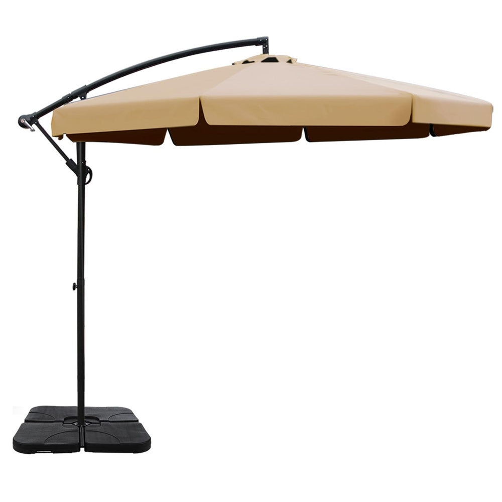 Beige cantilever patio umbrella with black pole and square base, side view