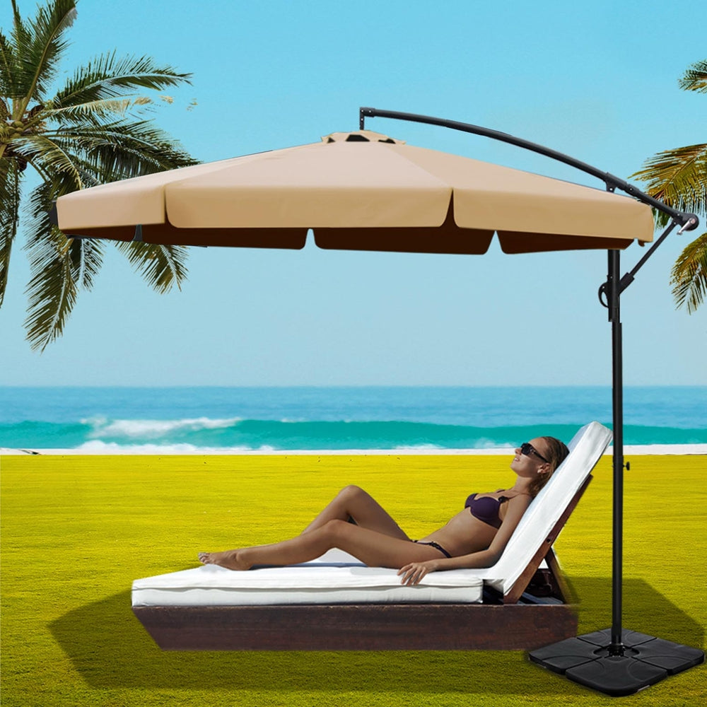 Beige cantilever patio umbrella over black weighted base with curved support arm
