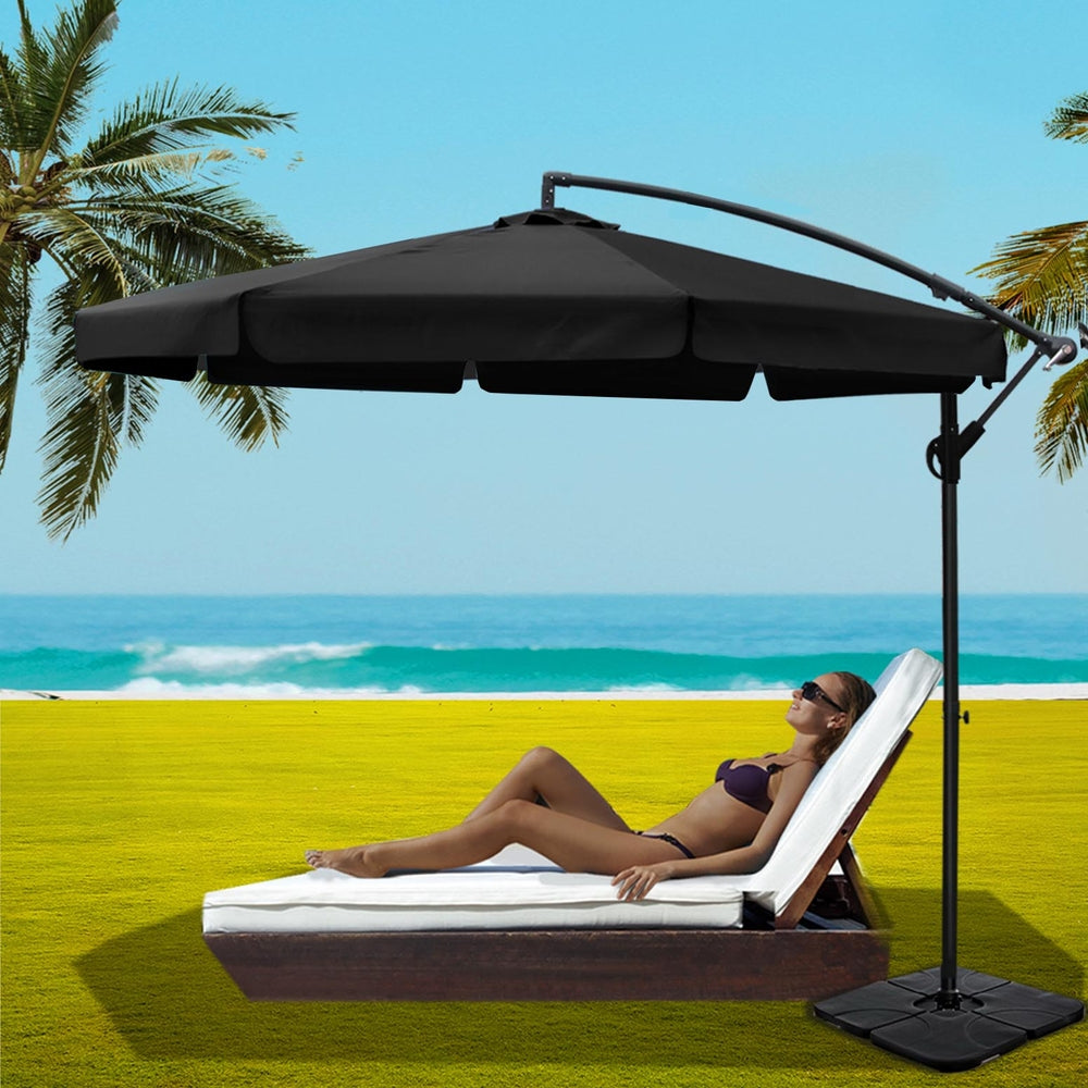 Black cantilever beach umbrella with extended canopy and square base beside lounge seating