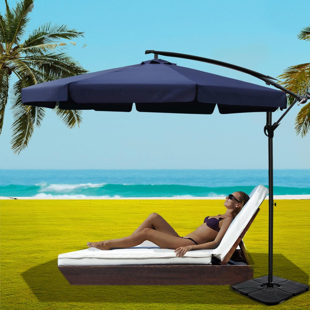 Navy cantilever patio umbrella with arched arm and black base beside seating