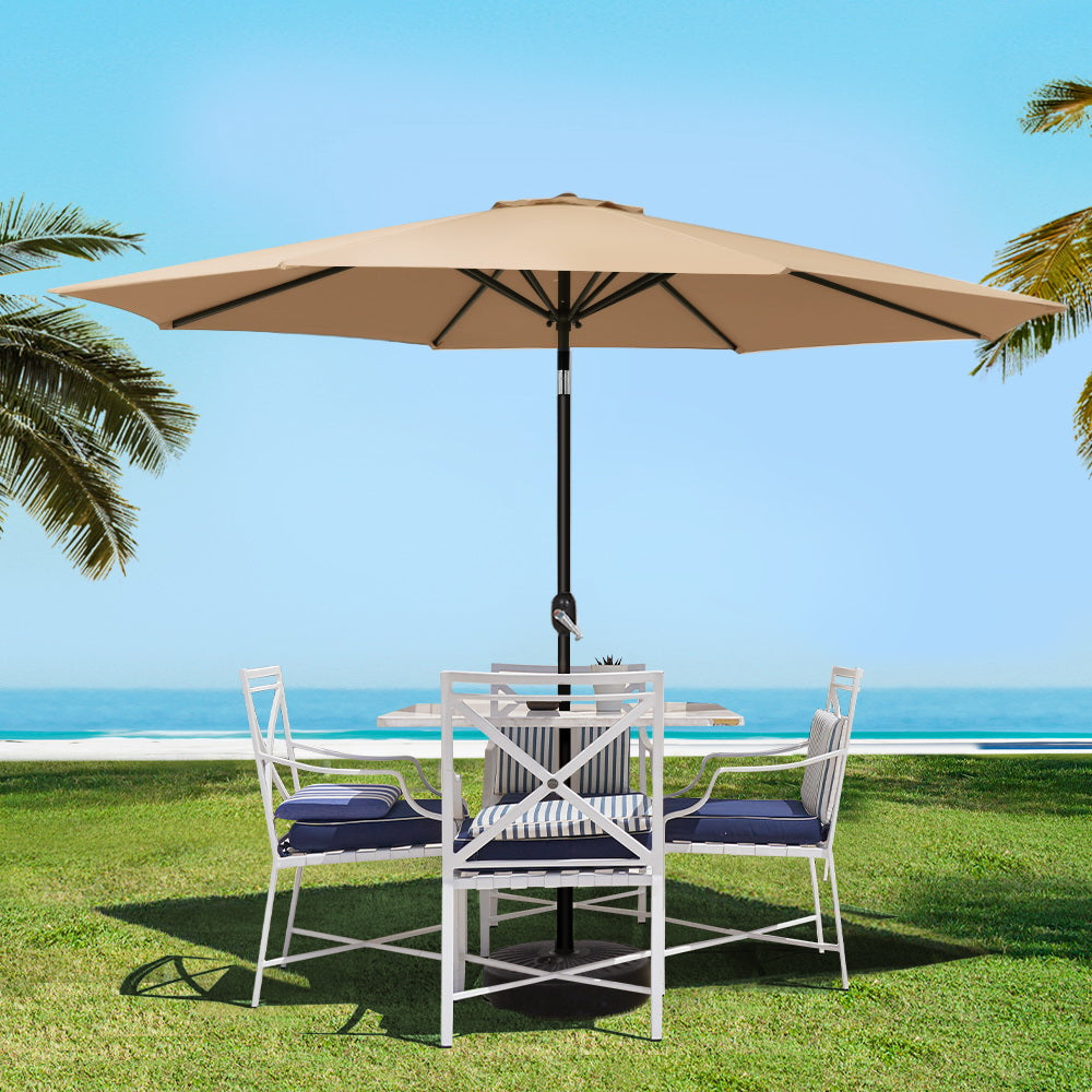 Beige outdoor umbrella with black pole above patio dining table and chairs