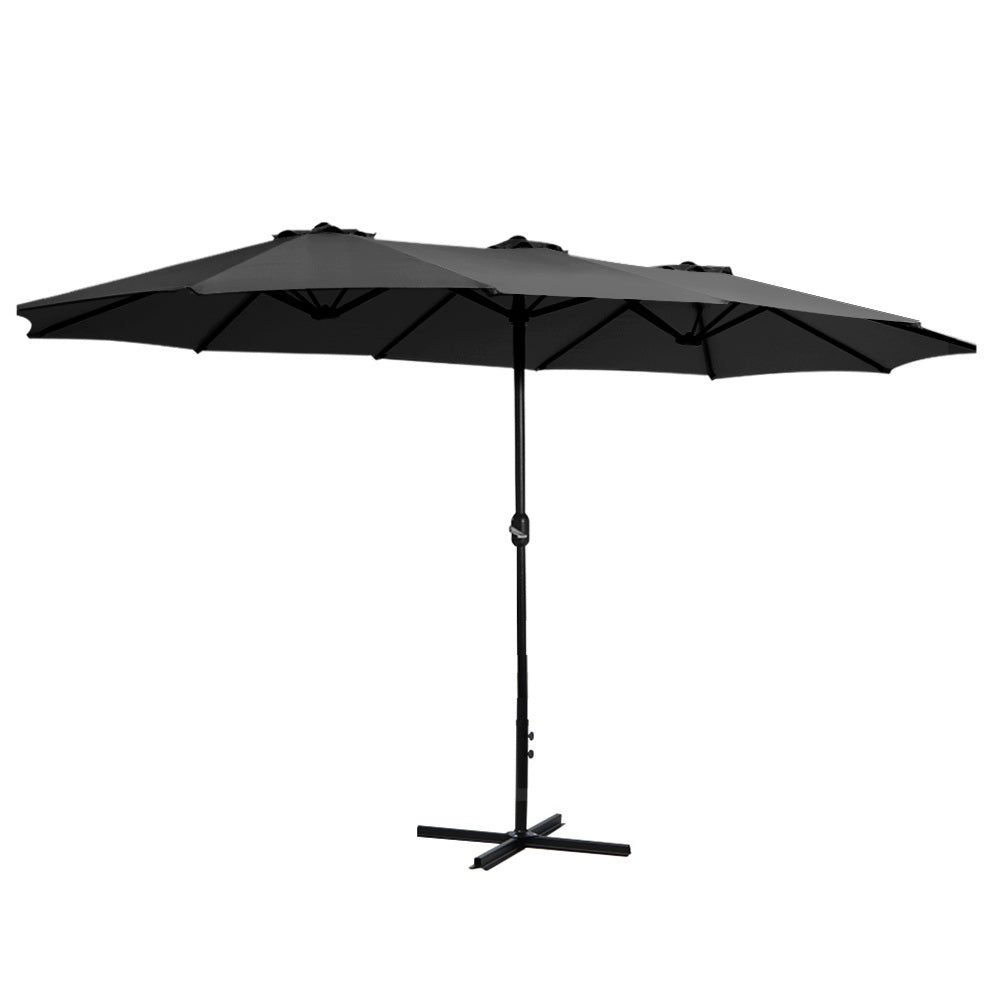Black outdoor umbrella with open canopy and center pole, mounted on a cross base.