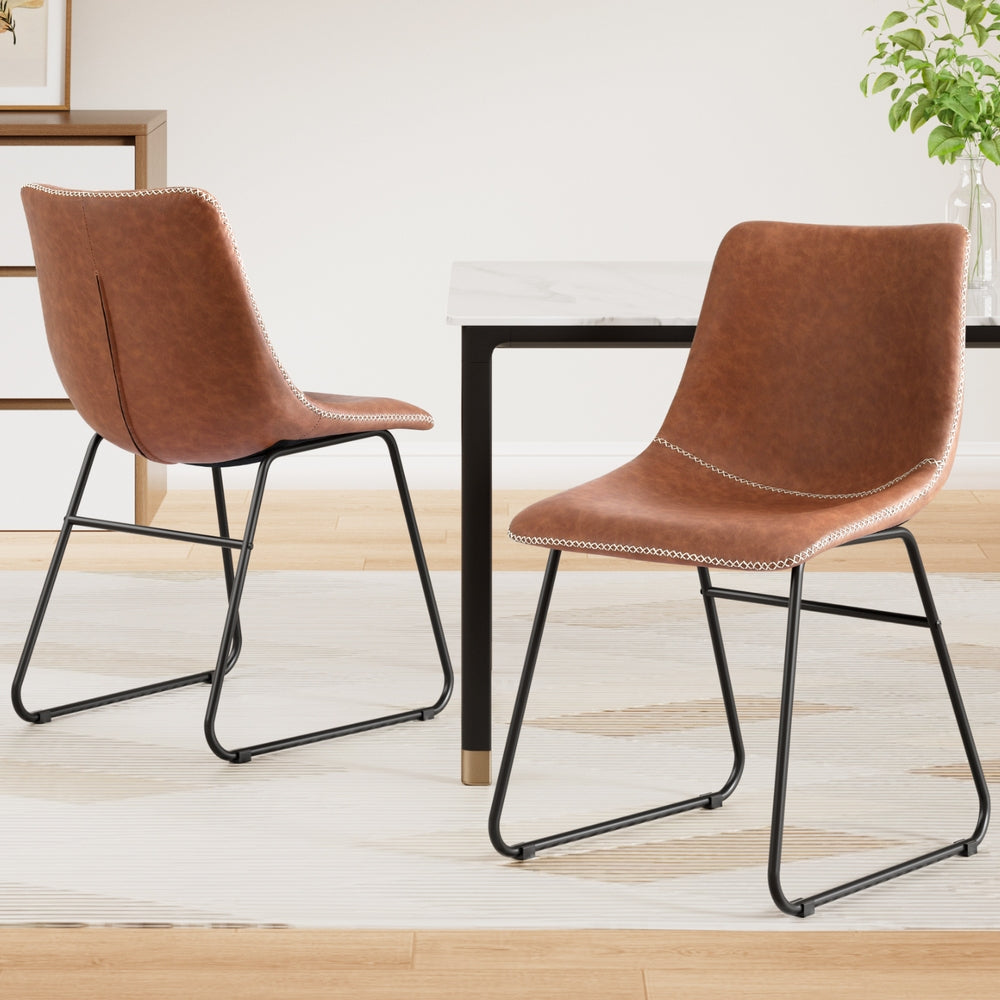 Two brown PU dining chairs with curved backs and stitched seats, black sled legs