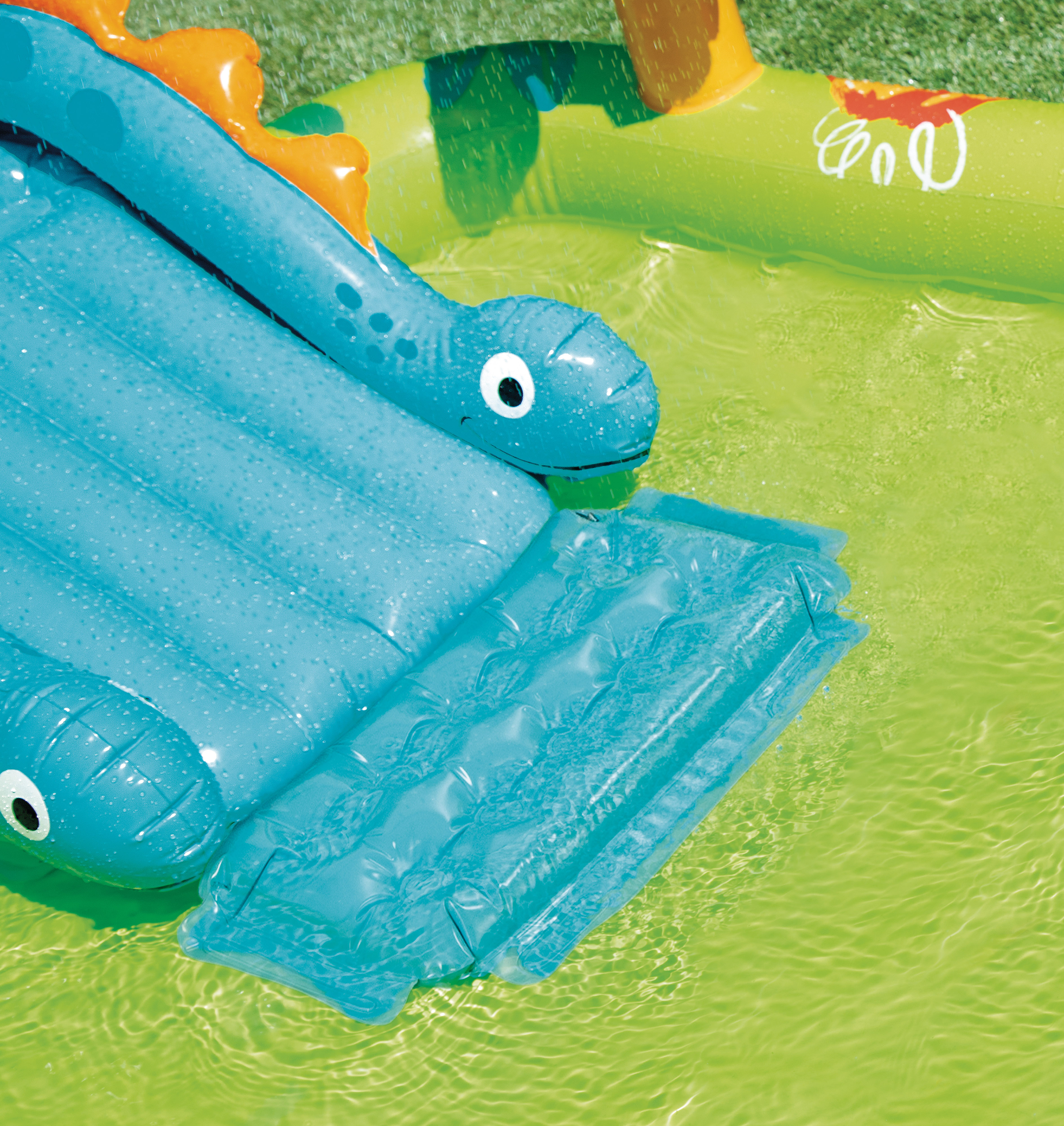 Blue dinosaur slide on a dinosaur inflatable play centre with clear splash pool