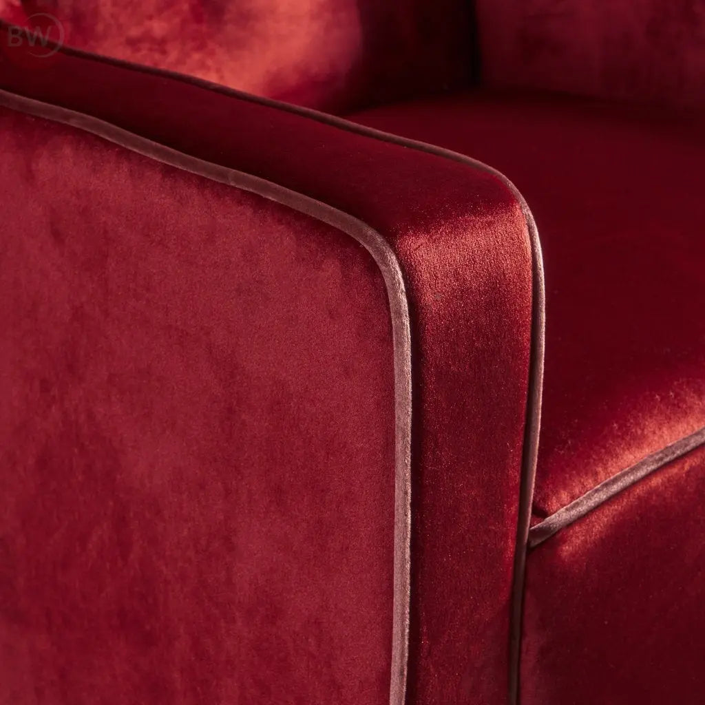 Velvet club armchair arm and side panel with dark trim, rich red upholstery