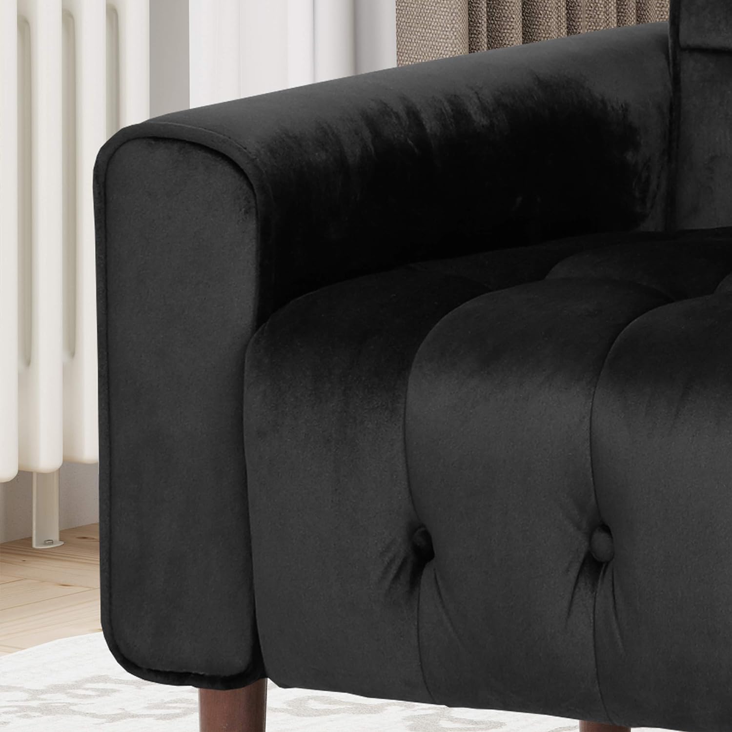 Black velvet armchair close-up with tufted backrest and rounded arm, thick fabric