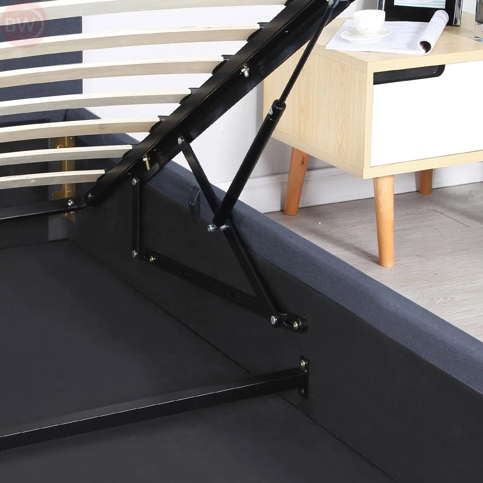 Charcoal gas lift bed frame showing raised base mechanism and storage compartment on the side