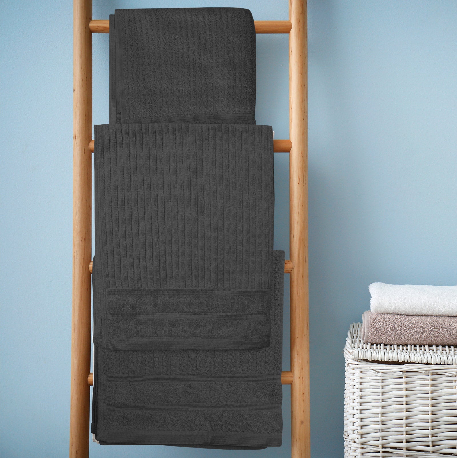 Folded bath towel set on a wooden rack, dark gray terry cloth