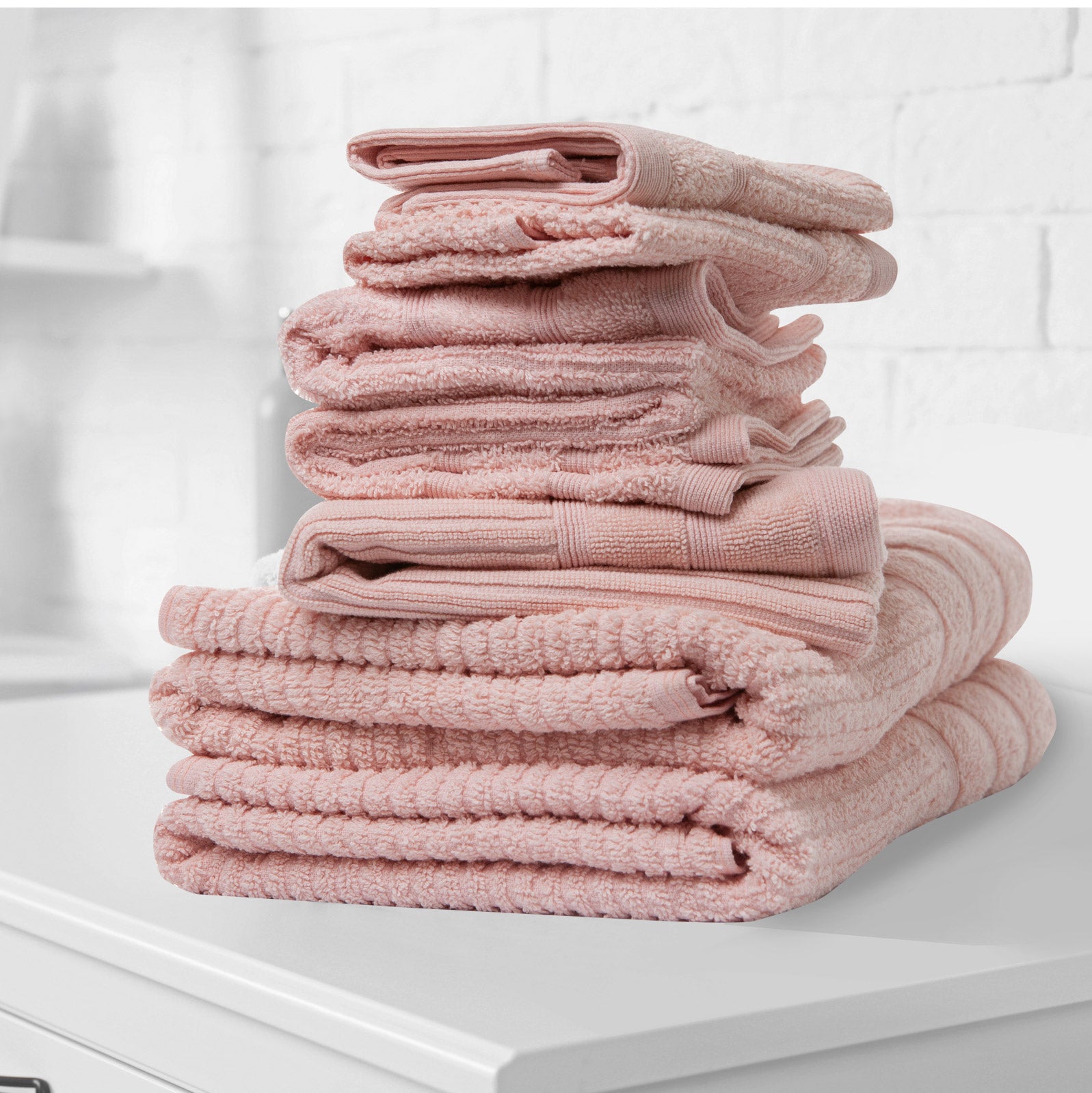 Blush bath towel set stacked with visible terry texture and folded edges.