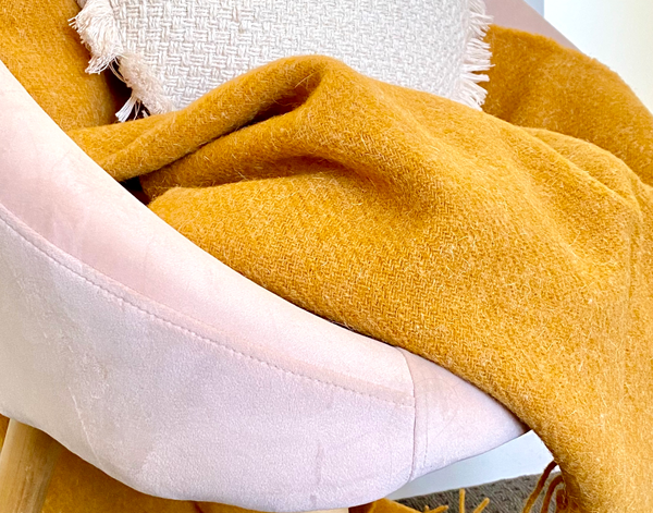 Mustard wool throw with textured surface and short fringes along the edge