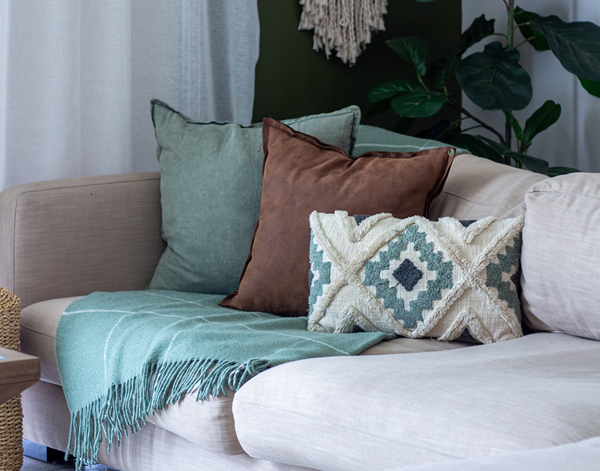 Sage striped wool throw blanket with fringes, draped on a couch