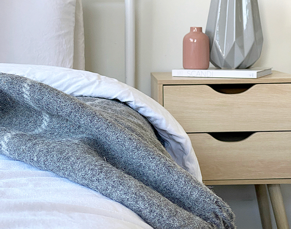 Grey striped wool throw draped over bed