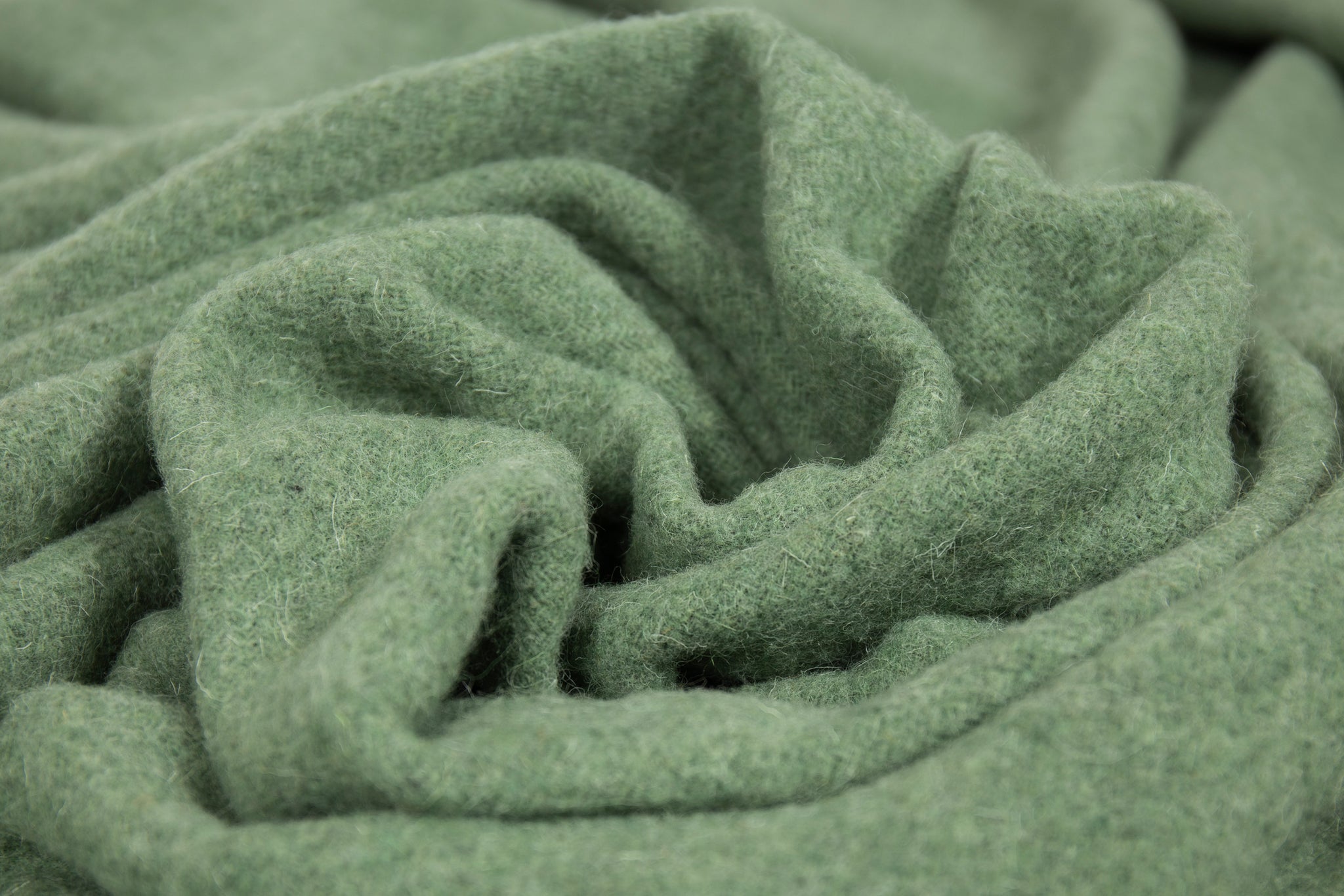 Sage green wool throw close-up showing soft woven texture