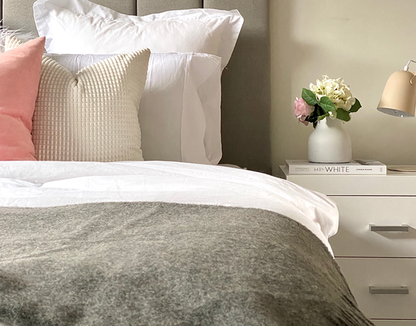 Grey wool throw blanket draped on a bed