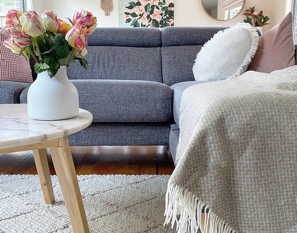 Merino wool and cashmere throw draped on sofa, light beige with fringed ends