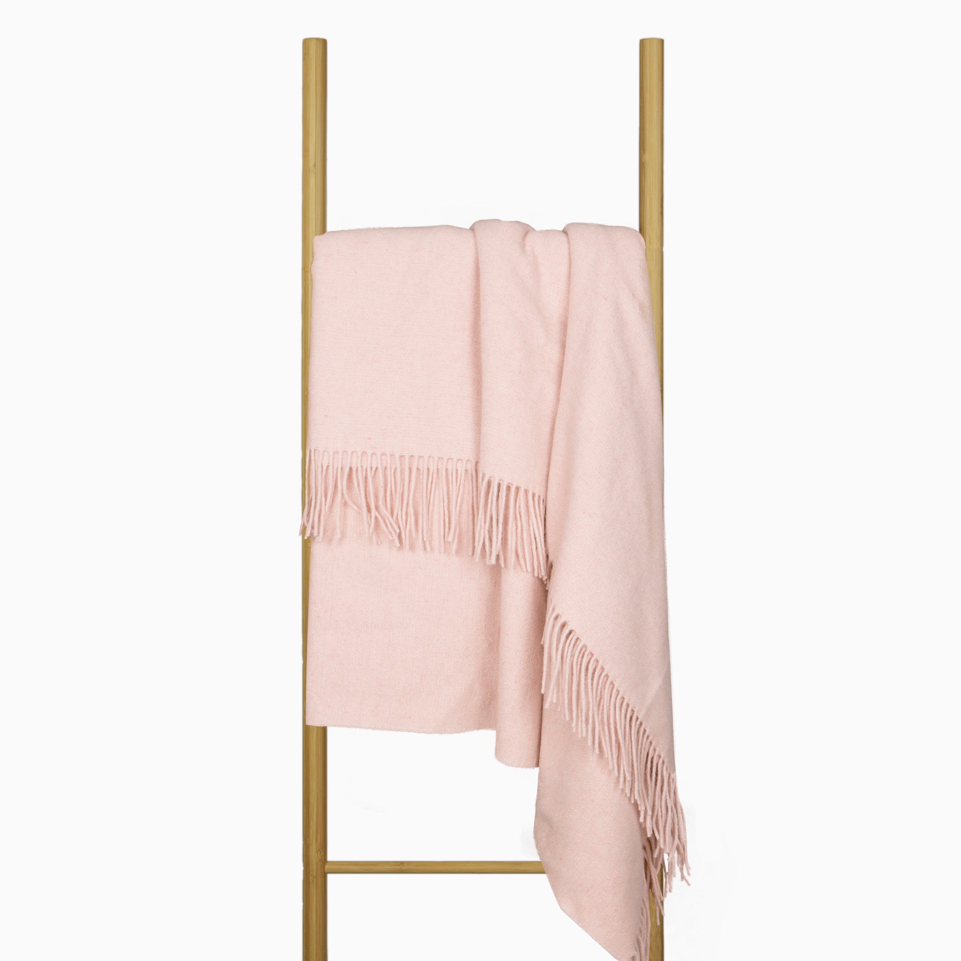 Blush throw blanket draped over stand with decorative fringe border