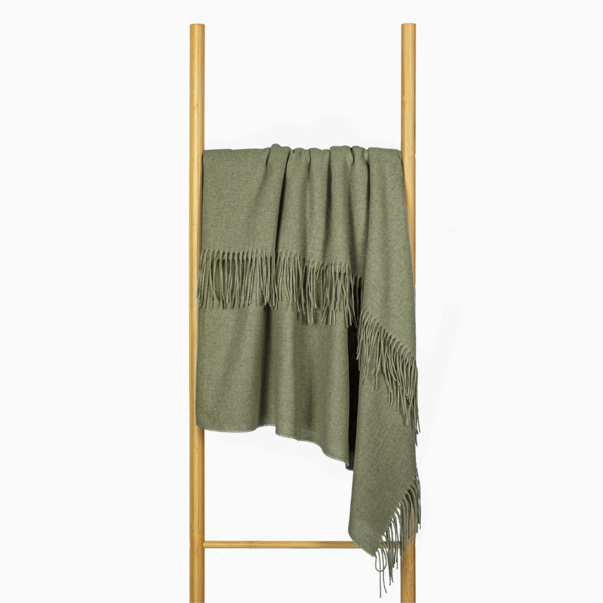 Olive throw draped over display stand, with tassel fringe and gathered hem