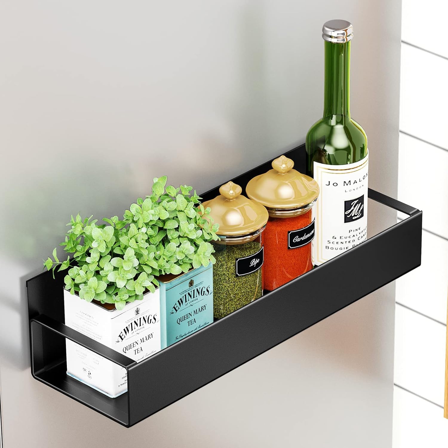 Black magnetic fridge shelf with tea tins, spice jars, and green glass bottle