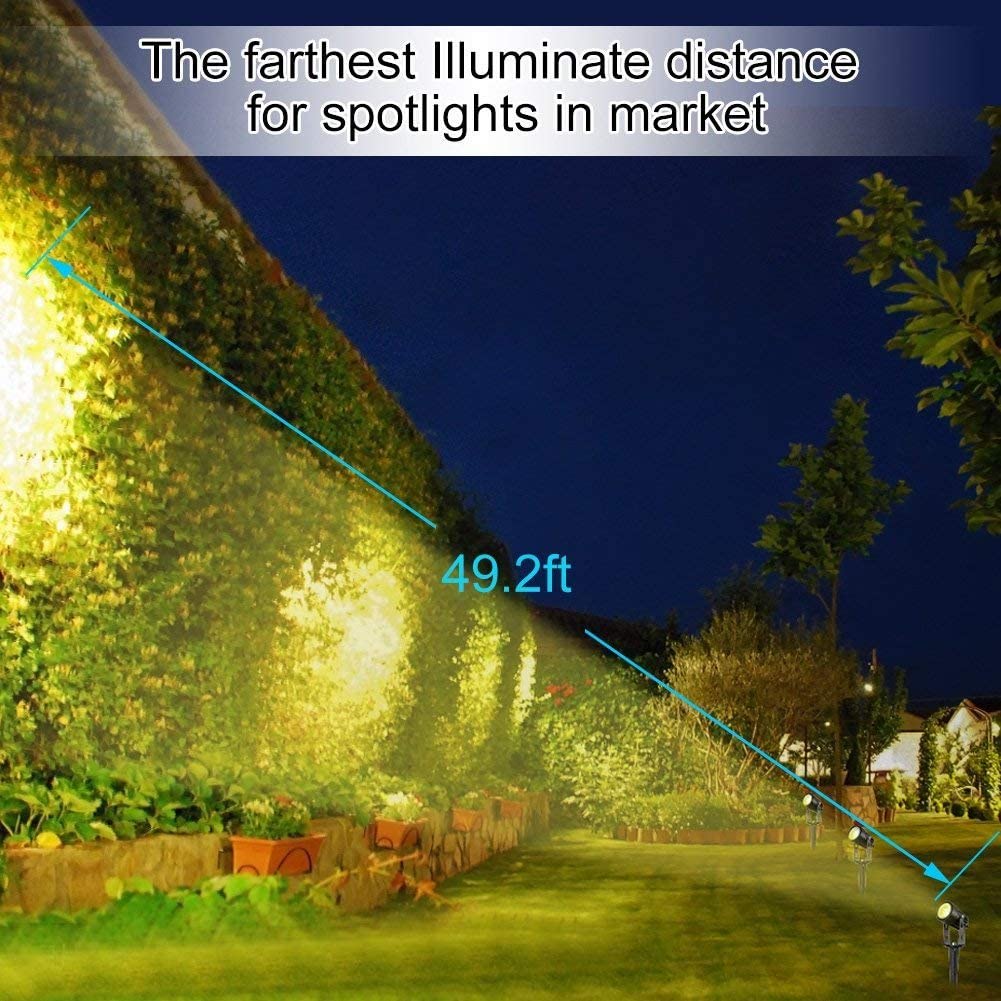 Black solar LED spotlight with spike stake and strong light beam across yard